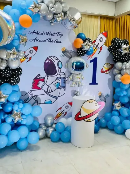 Let's blast off with a space-themed first birthday party. This "First Trip Around the Sun" setup includes a custom backdrop, astronaut and rocket cutouts, and a balloon garland with planet and star foil balloons to create an out-of-this-world experience.