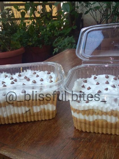 My Banoffee Pie in larger takeaway containers, perfect for sharing. The layers of cream and biscuit are topped with chocolate chips.