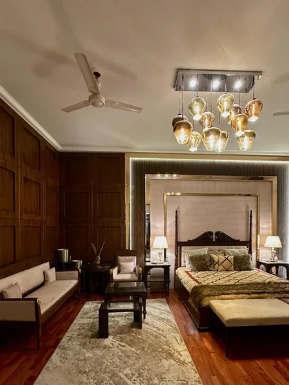 We created a "Contemporarised Elizabethan" feel for this elegant bedroom. The design is anchored by eleven foot tall, handcrafted wall paneling in veneer and fabric, a classic four poster bed, and a custom nesting coffee table made from repurposed carved teak wood.