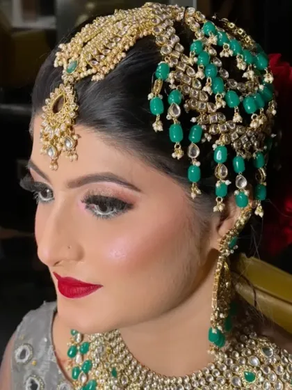 We specialize in creating breathtaking Pakistani bridal looks. This makeover highlights the intricate beauty of a traditional passa and jhoomar set with green beads, paired with a bold red lip and defined eyes. We ensure every detail, from the makeup to the dupatta setting, is perfect.