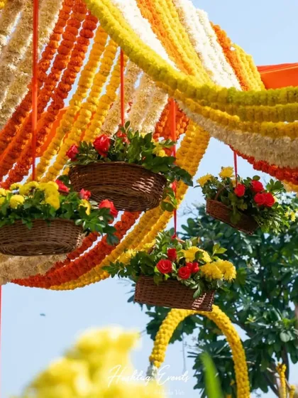 Traditional decor can be incredibly beautiful. For this event, we created a dense canopy of yellow and orange marigold garlands, with hanging floral baskets adding a fresh, festive touch to the celebration.