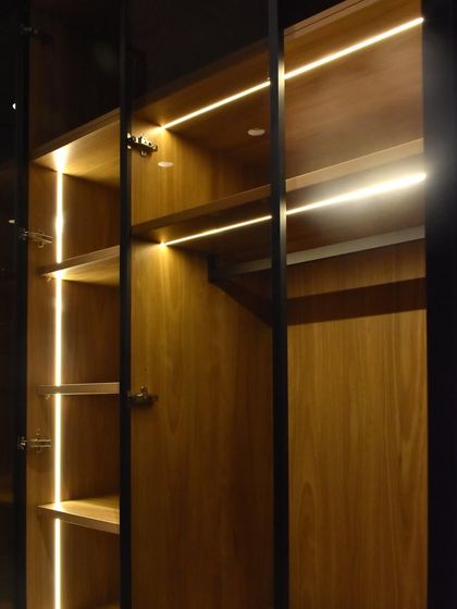 Here you can see the combination of shelf and rod lighting within a single wardrobe unit. We use high-quality German hardware for the soft-close hinges on the glass doors.