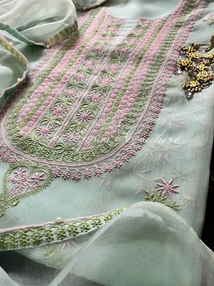 A close-up of the neckline, styled with traditional earrings, showing the intricate floral embroidery.