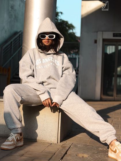 A straight-on shot that highlights the attitude of the outfit, complete with bold white sunglasses and a relaxed, powerful stance.