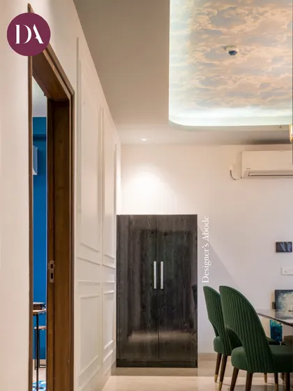 A view from the passage into the dining room, where deep green chairs and a sky-printed ceiling wallpaper create a unique and chic atmosphere. This shows our approach to designing every part of the home, including transitional spaces.