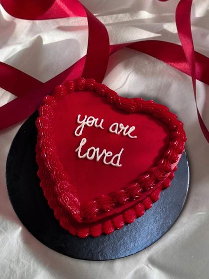 A simple, sweet message on a red heart-shaped bento cake: "you are loved." It's a small cake with a big heart, perfect for a personal gesture.