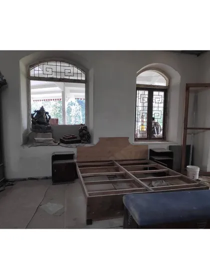 A bedroom during the restoration process. The original arched windows are preserved while new furniture frames are brought in, demonstrating how we plan for modern living within the historic architectural shell.