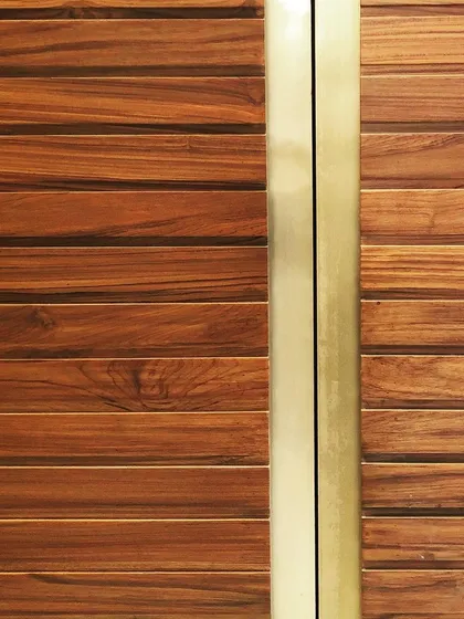 A close-up showcasing the magic of combining Indian Teak wood with brushed brass. This detail from a piece of custom furniture highlights the beautiful contrast between the warm, natural grain of the wood and the sleek, metallic finish.