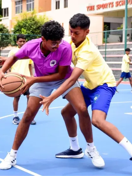 Two young athletes battle for possession during a competitive basketball game on our outdoor court, showcasing the intensity and spirit of sportsmanship we foster.