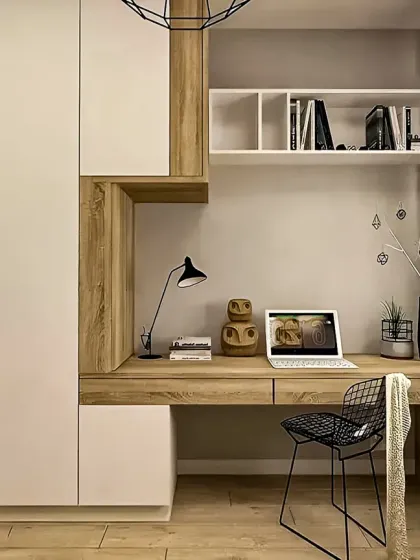 A cozy and modern study nook built into a bedroom. The design combines white and wood-tone cabinetry, providing a functional desk space with integrated storage and shelving.