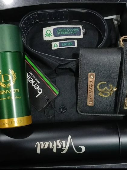 A sleek all-black hamper with a UCB shirt, a personalized wallet and keychain, and a name-engraved flask.