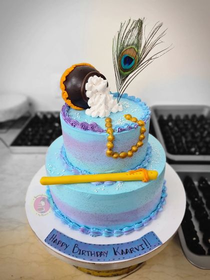 A two-tier Janmashtami cake with a lovely pastel watercolor effect.