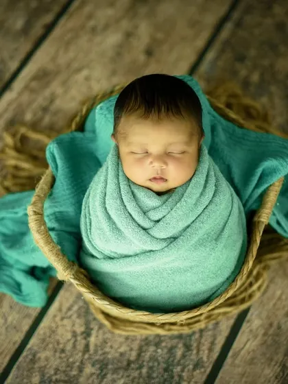 A wider shot showing the beautiful textures of the wooden floor, the rustic basket, and the soft green wrap, creating a complete visual story.