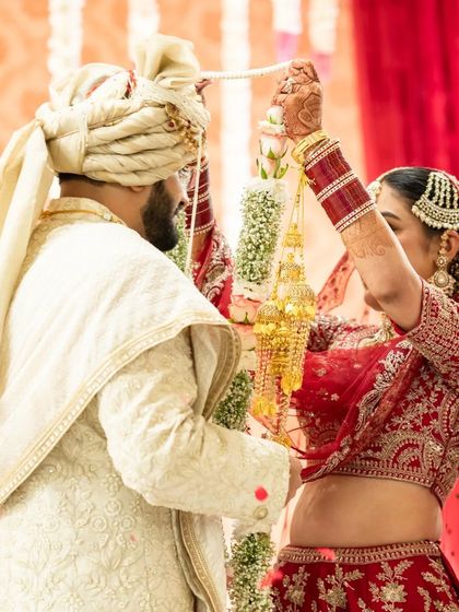 The varmala ceremony, a key ritual in an Indian wedding. This shot captures the bride placing the garland on the groom.