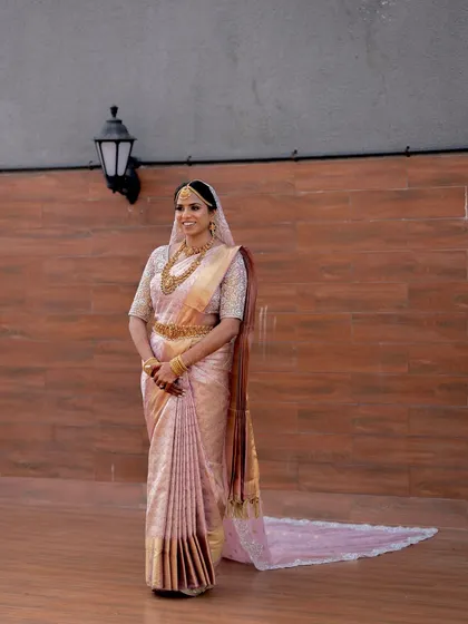 A full-length view of the bride in her elegant pink silk saree, looking serene and beautiful.