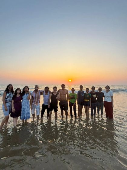 A beautiful sunset photo with the group standing in the shallow waves.