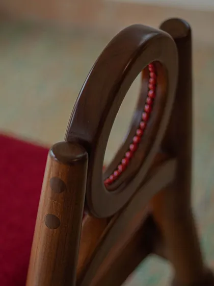 A series of images detailing the Manjadi chair, from its hand-turned legs inspired by the seed pod to the vibrant red upholstery. These shots highlight the craftsmanship and the deep cultural narrative behind this unique design.