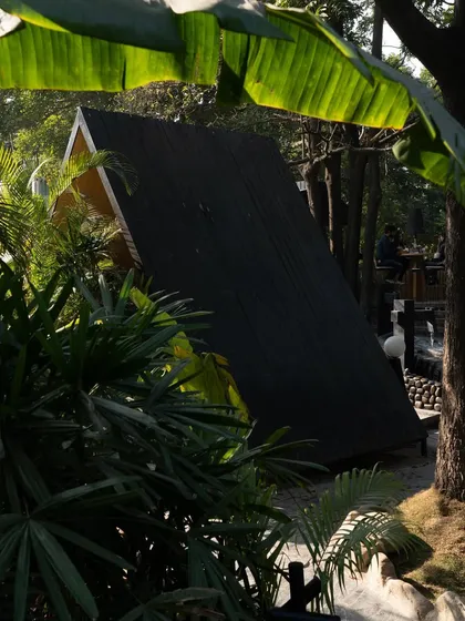 A glimpse of a dining pod through the dense leaves of a banana tree, emphasizing the feeling of being completely immersed in nature.