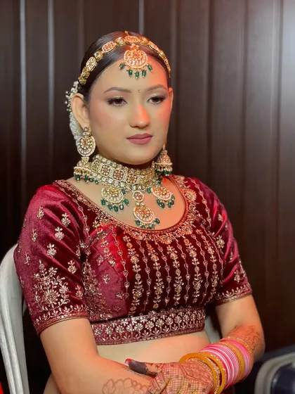 A portrait of traditional glamour. The bride's velvet lehenga and emerald jewelry create a rich, luxurious look, while her makeup is kept elegant and defined.