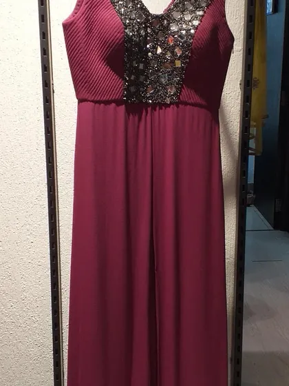 This wine-colored gown features a pleated bodice with a heavily embellished mirror-work panel. It's a modern and chic option for an evening party or cocktail event.