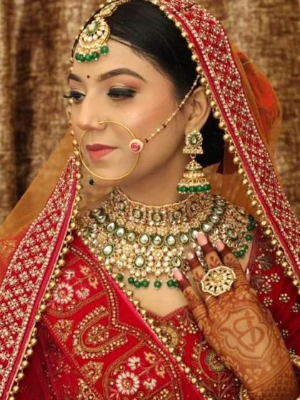 This bride is the picture of elegance. The makeup features soft green and gold eyeshadow to match her jewelry, along with a flawless base and a classic bridal nath.
