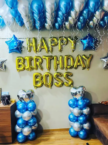 A fun "Happy Birthday Boss" decoration for an office celebration. The setup uses blue and silver balloons and large gold foil letters.