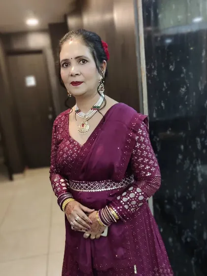 A full view of the client's party look. She is wearing an Anarkali suit with a belt, and the makeup is kept classic with a bold lip and defined eyes.