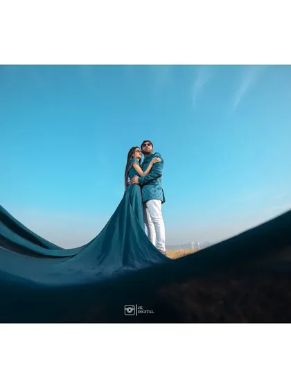 A creative shot using the bride's flowing gown to frame the couple against a brilliant blue sky. This technique adds depth and a grand scale to the portrait.