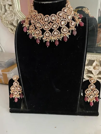 A rose gold choker set with ruby-colored drops. This is a modern and elegant rental choice for a cocktail party or reception.