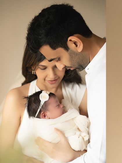 An intimate, close-up family portrait. This angle, looking down as the parents cherish their newborn, creates a sense of being enveloped in their love and happiness.