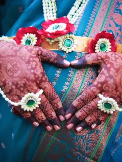 The mom-to-be making a heart shape with her hands over her belly. This pose beautifully captures the love and anticipation of the moment, with the custom mehendi at the center.
