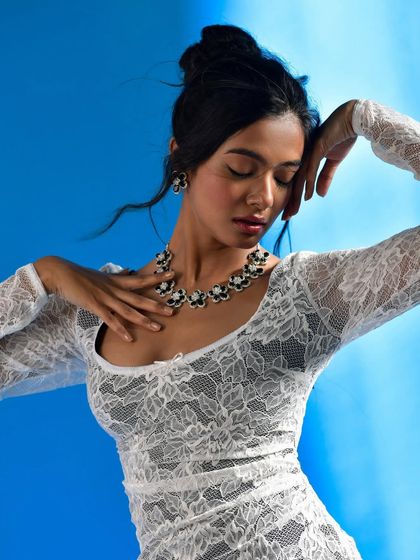 A graceful, flowing pose that shows how the jewelry moves with the body. The model's hand gently touching her neck brings the viewer's eye to the statement necklace.