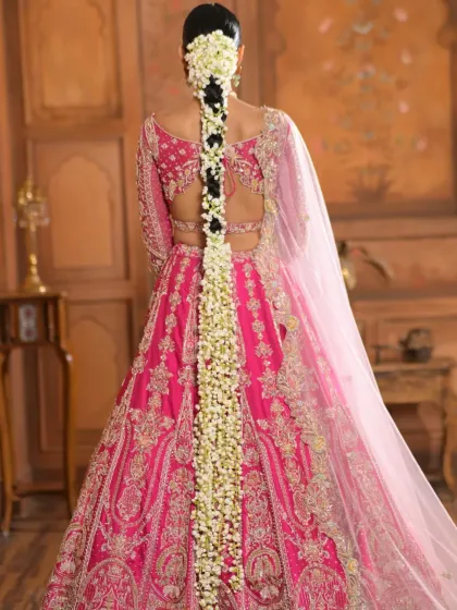 A full view of an elaborate traditional bridal braid created for a designer lookbook. This floor-length hairstyle is meticulously woven and adorned with fresh gajra, designed to complement the grandeur of the couture lehenga.
