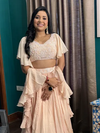 A full-length shot of the client, showcasing her beautiful ruffled lehenga and the soft, elegant makeup that completes the look.