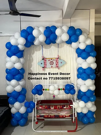 For a simple and sweet naming ceremony at home, I created this blue and white balloon arch around the baby's cradle. A small, decorated nameplate hangs above the cradle to complete the look.