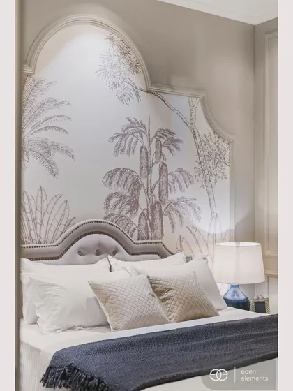 A close-up of a serene bedroom featuring a custom-arched headboard with a delicate tropical wallpaper. The soft, layered bedding and muted color palette create a tranquil and inviting mood, perfect for a personal sanctuary.