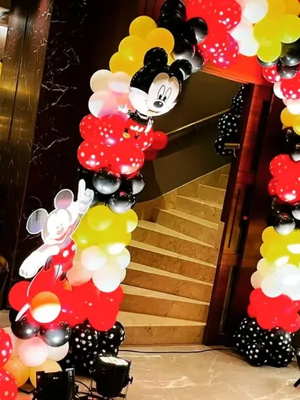 A cheerful Mickey Mouse themed balloon arch at the entrance to a birthday party. The iconic red, black, and yellow colors instantly signal a fun-filled celebration ahead.