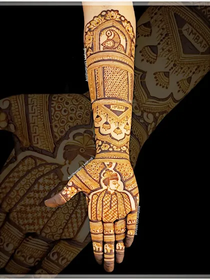 A full arm bridal design featuring a groom's portrait on the palm. The design is filled with traditional patterns, including jhumka and peacock motifs.