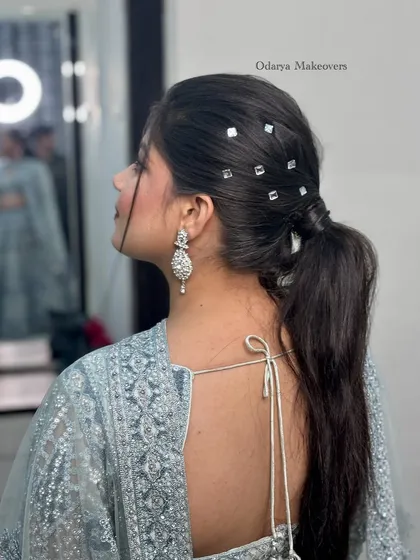 This trendy ponytail hairstyle is a great choice for a modern reception or cocktail look. The mirror-work accessories add a unique and glamorous touch.