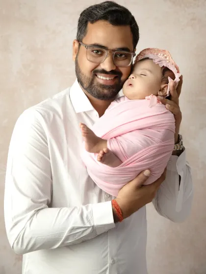A proud father smiles as he holds his tiny, sleeping newborn, showcasing the special bond between a dad and his new baby.