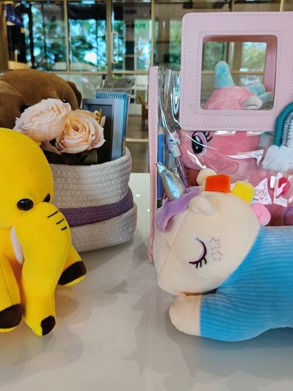 A collection of adorable plush toys, including unicorns and a yellow bear, ready to be added to kids' hampers.