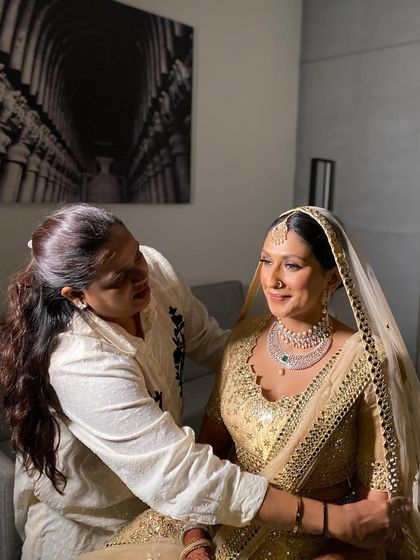 A sweet moment between the makeup artist and the bride as she gets ready. I created a sleek, clean bun with white roses for her elegant look.