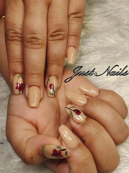 A simple yet elegant design featuring a nude base with delicate, hand-painted red flowers on accent nails.