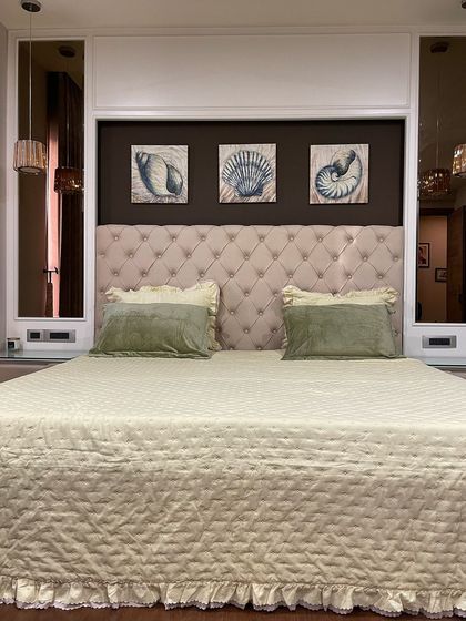 A cozy and classic master bedroom with a plush, button-tufted headboard. We flanked the bed with mirrors to make the room feel wider and reflect the light from the pendant lamps.