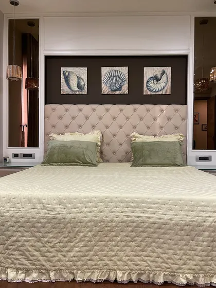 A cozy and classic master bedroom with a plush, button-tufted headboard. We flanked the bed with mirrors to make the room feel wider and reflect the light from the pendant lamps.