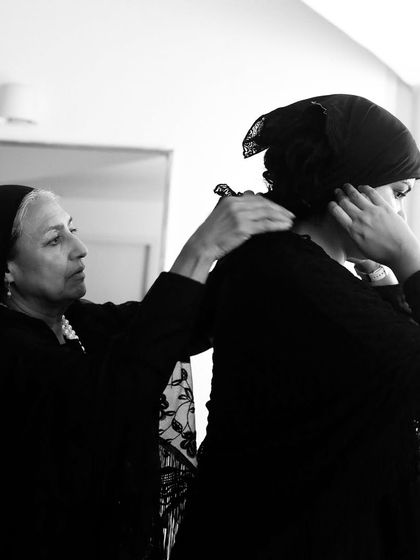 An actor helps another with her costume, showing the teamwork involved in our productions.