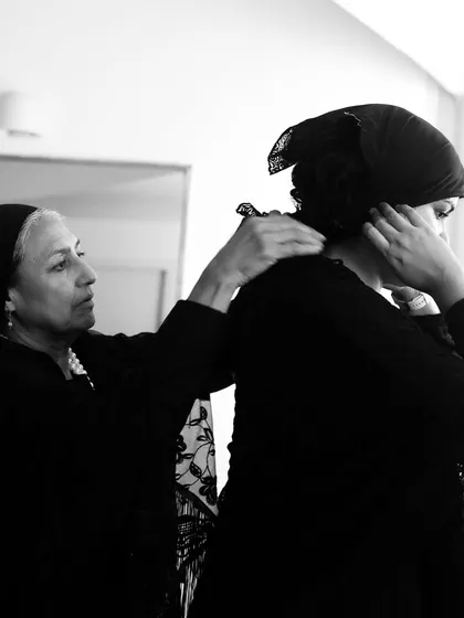 An actor helps another with her costume, showing the teamwork involved in our productions.