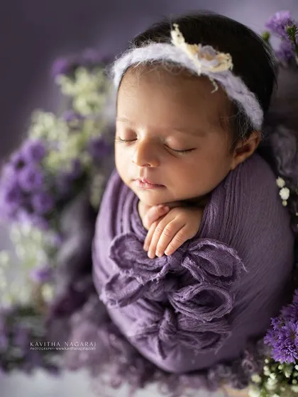 A newborn girl wrapped in a beautiful shade of purple, surrounded by delicate flowers. This is one of my all-time favorite images, capturing a sense of royalty and peace.