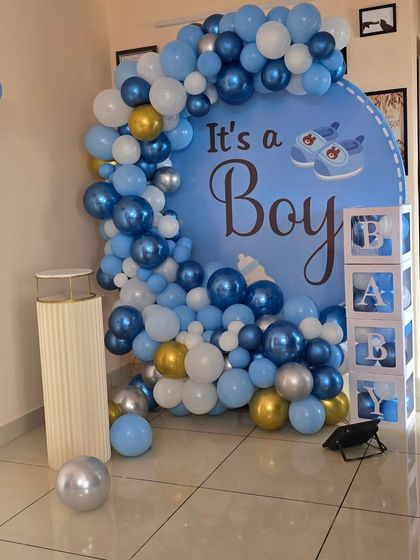 The main backdrop for the 'It's a Boy' celebration, featuring a circular print and a full balloon garland.