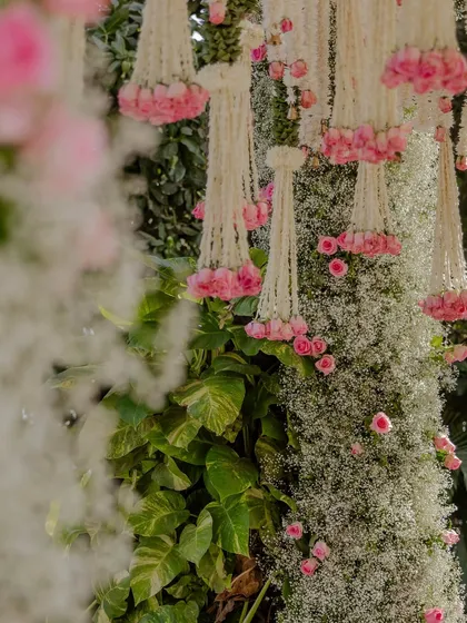 A detailed view of the floral pillars, combining dense baby's breath with clusters of pink roses and hanging tuberose strings for a textured, multi-layered look.